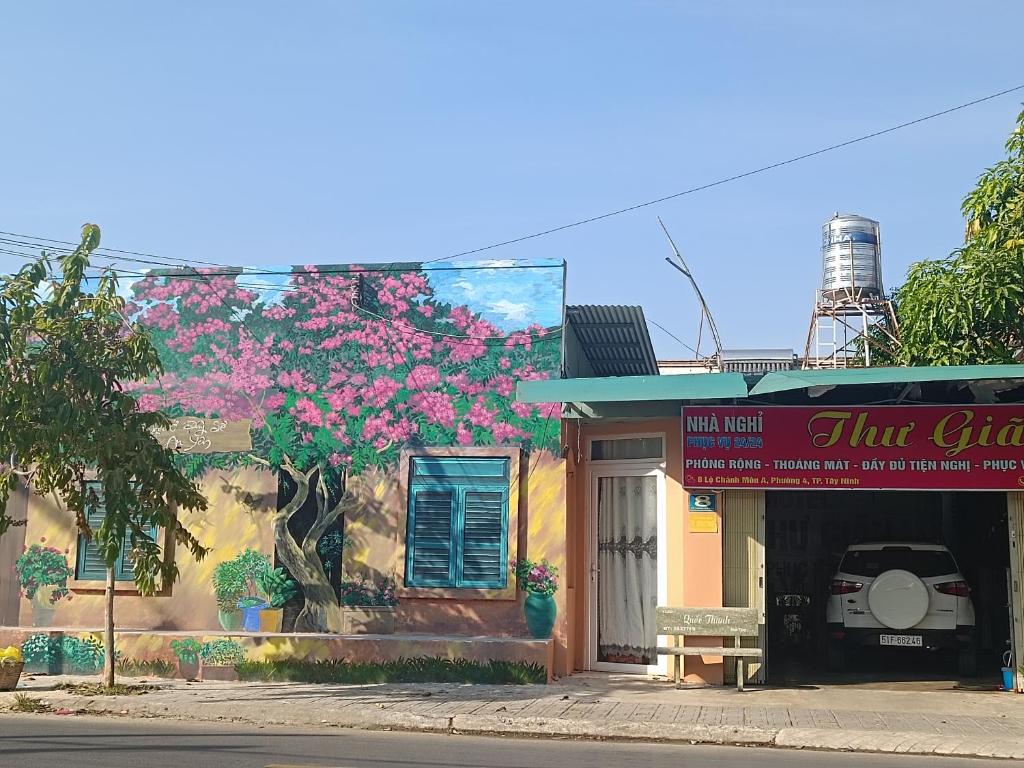 un edificio con un albero con fiori rosa di Nhà Nghỉ Thư Giản a Tây Ninh