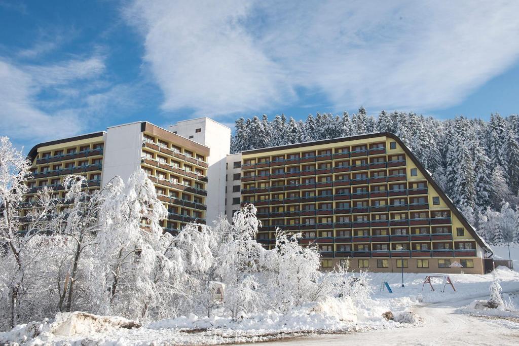 a building with snow covered trees in front of it at Hotel SOREA ĽUBOVŇA in Stará Ľubovňa