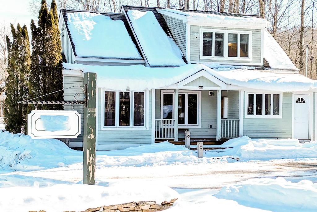 a house covered in snow with a street sign in front at Hit the Slopes! in Intervale