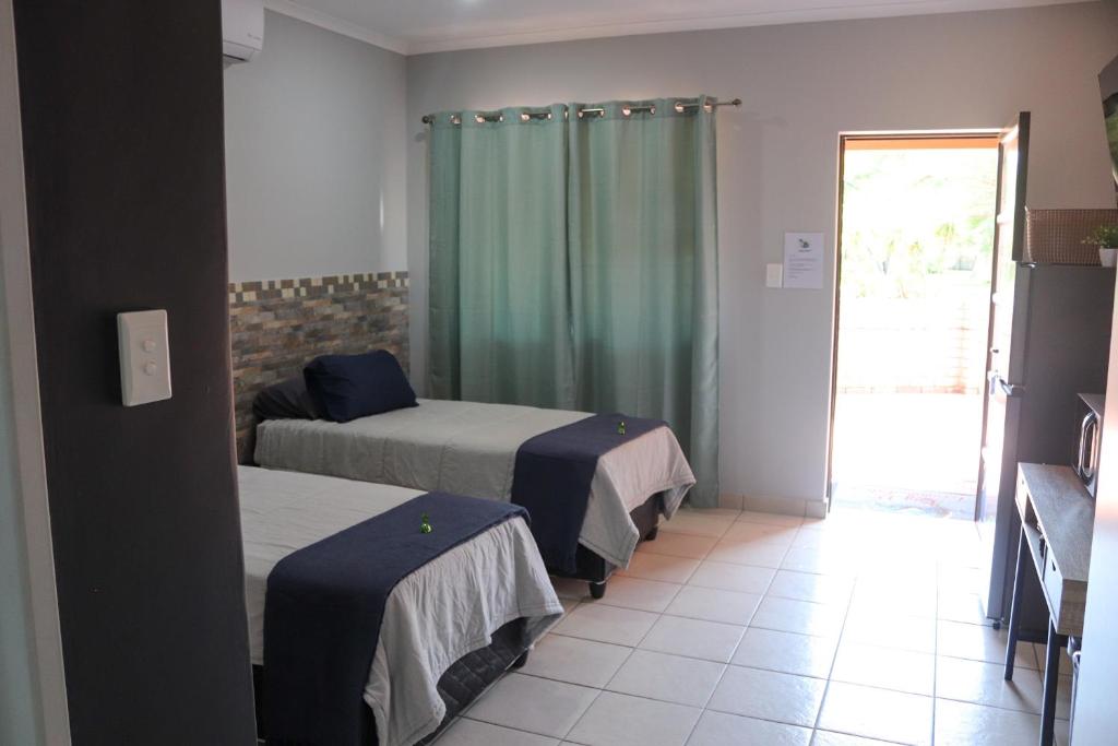 a bedroom with two beds and a door to a patio at Big D Accommodation & guesthouse in Northam