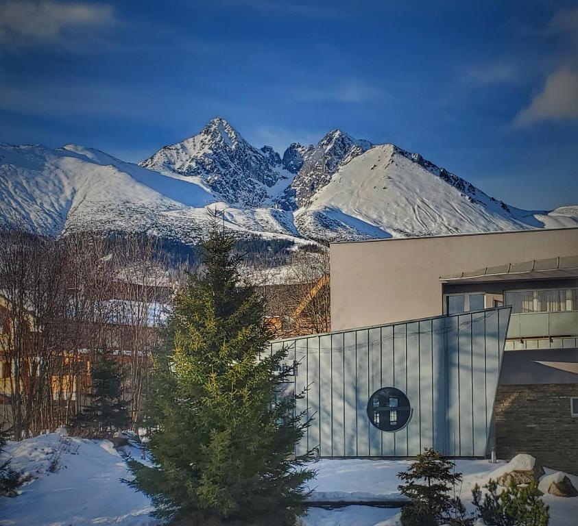 ein Gebäude mit einem Weihnachtsbaum vor schneebedeckten Bergen in der Unterkunft Hotel SOREA URÁN in Tatranská Lomnica