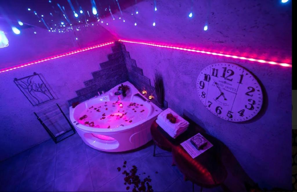 凱爾採的住宿－APARTAMENT NEON JACUZZI W RYNKU KIELCE z Parkingiem-Możliwosć wyżywienia，紫色的客房设有浴缸和时钟