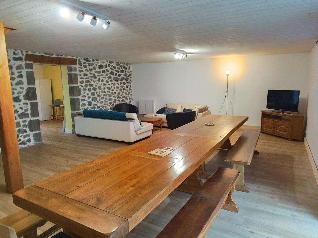uma sala de estar com uma mesa de madeira e um sofá em Grande maison 7 chambres em Cheylade