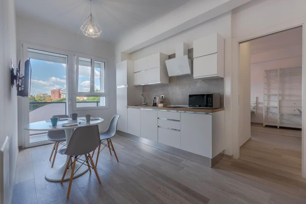 een keuken met witte kasten en een tafel en stoelen bij BO 40 SELF CHECK-IN - Appartamento Fiera-Tecnopolo in Bologna