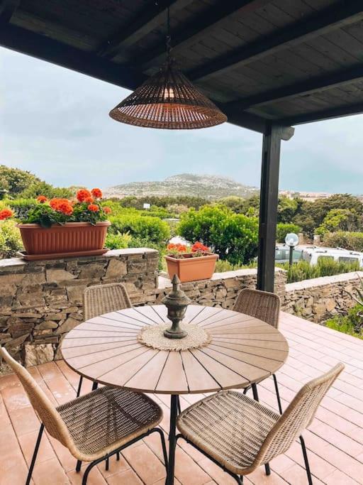a wooden table and chairs on a patio with flowers at n4 RELAXING SEAVIEW APARTMENT in Stintino