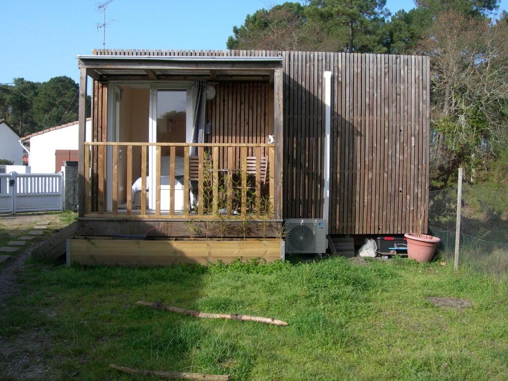 Cabaña de madera con porche y un gato en el patio en Chambre nature en Arès