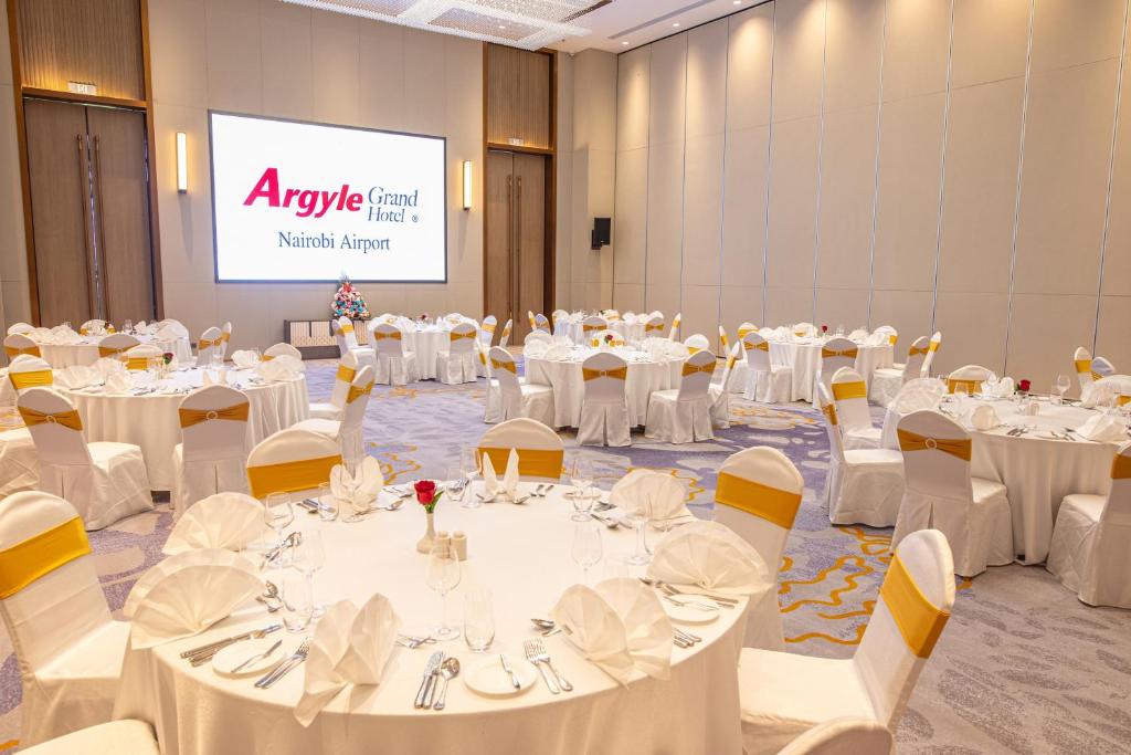 a conference room with white tables and chairs and a screen at Argyle Grand Hotel Nairobi Airport in Nairobi