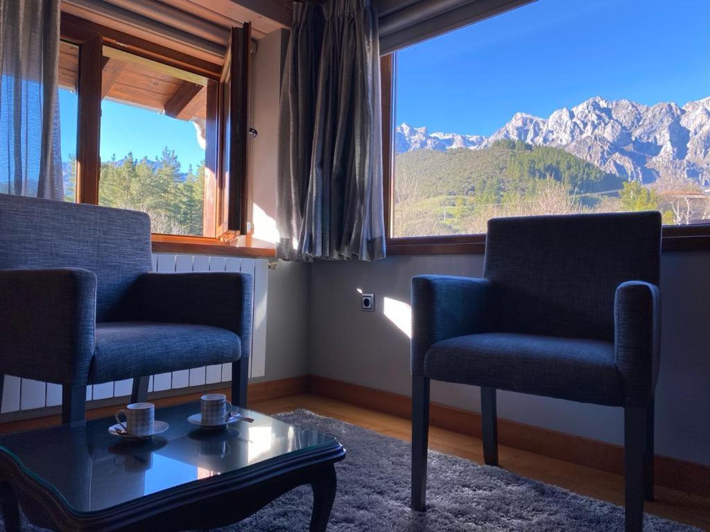 een woonkamer met 2 stoelen, een tafel en een raam bij Picos de Europa Suites and Rooms in Turieno