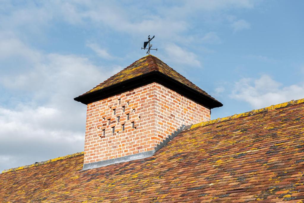 una torre di mattoni sul tetto di un edificio di Pigeon House - Unique Barn with private garden, hot tub and wood burner a Shrewsbury