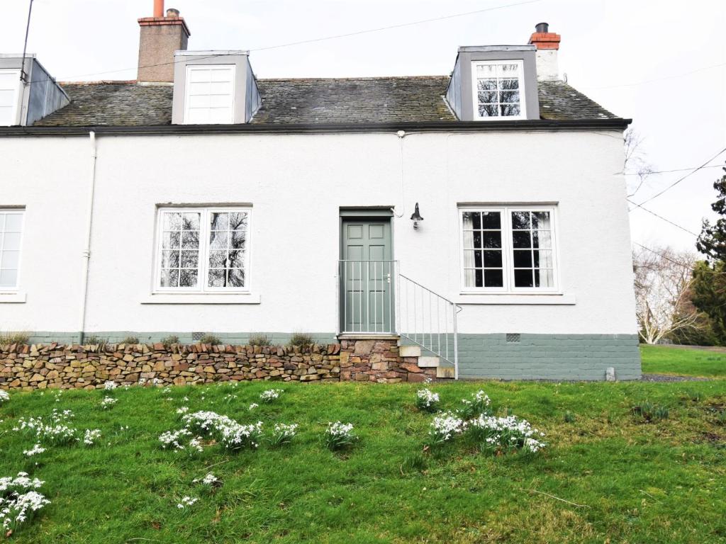 a white house with a stone wall and a green door at 2 Bed in Lauder 91383 in Lauder