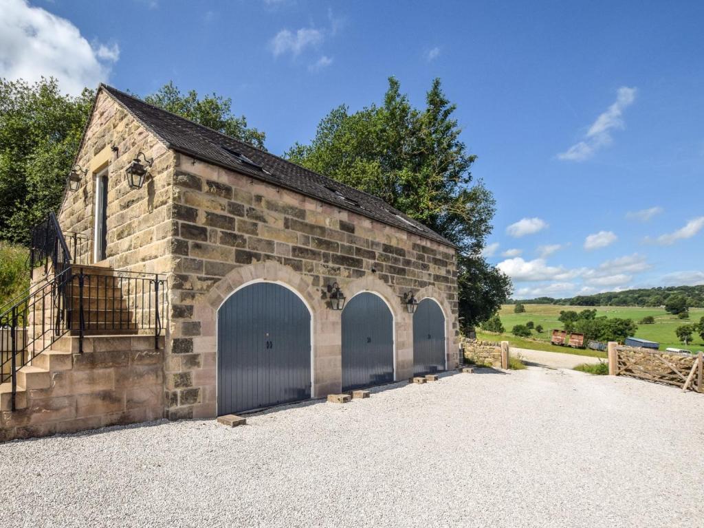 ein altes Backsteingebäude mit drei Garagentüren in der Unterkunft 1 Bed in Peak District 91367 in Youlgreave