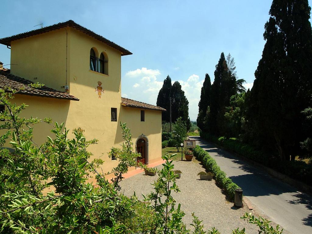 un edificio amarillo con un camino junto a una casa en Tenuta Il Corno Agriturismo en San Casciano in Val di Pesa