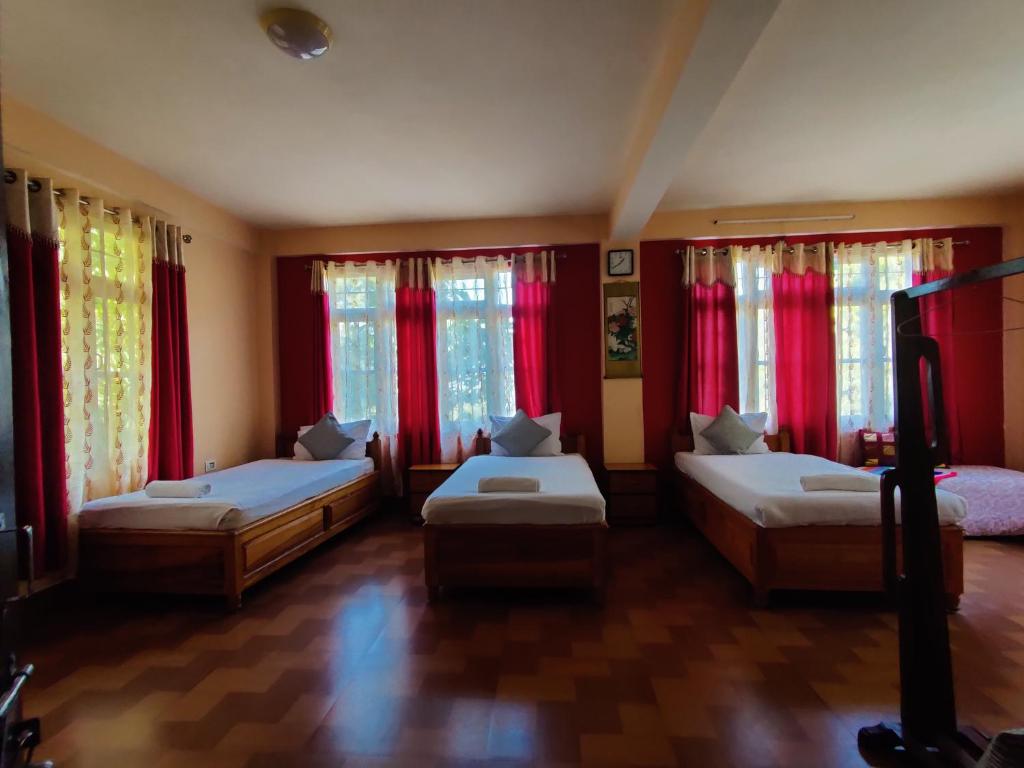 a bedroom with two beds and red curtains at The Shire Kalimpong in Kalimpong