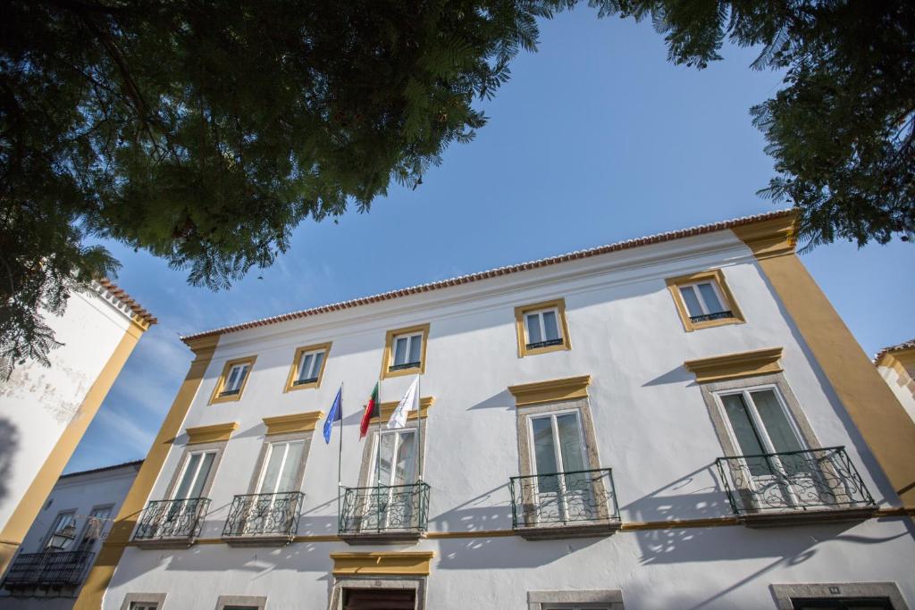 - un grand bâtiment blanc avec deux drapeaux dans l'établissement HI Évora – Pousada de Juventude, à Évora