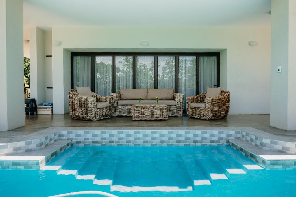 a pool with wicker chairs and a couch in a house at Ruzelle Family House in Hazyview