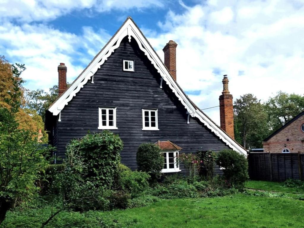 une maison noire avec deux cheminées au-dessus d'une cour dans l'établissement Gardener's Cottage, Knebworth Park, à Knebworth
