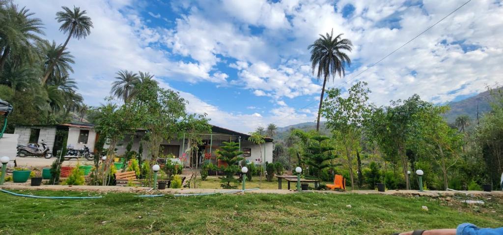 a house with palm trees in front of it at Palm Valley Farmhouse in Mount Ābu