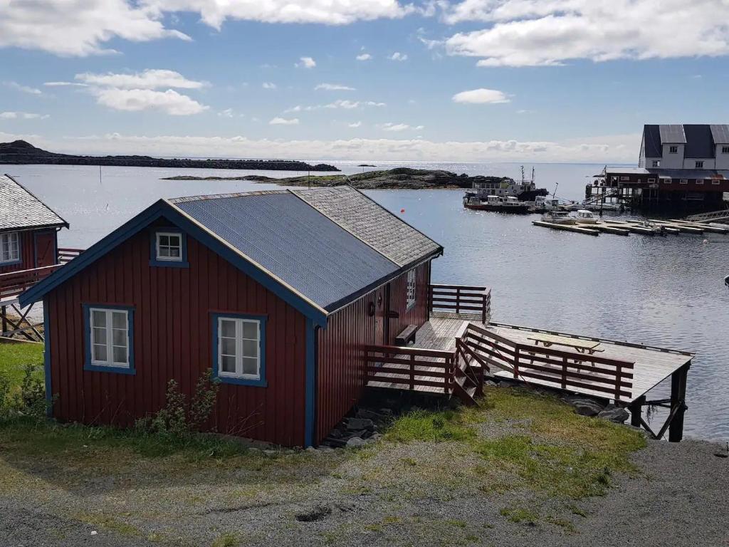 ein kleines rotes Haus mit einer Anlegestelle im Wasser in der Unterkunft Explorers Cabin Lofoten Edge in Sørvågen