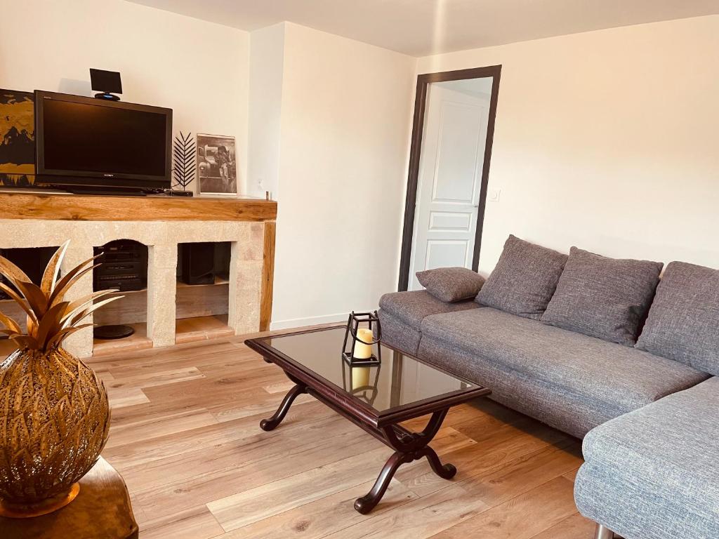 una sala de estar con un sofá y una mesa en Maison de campagne, en Saint-Santin-Cantalès
