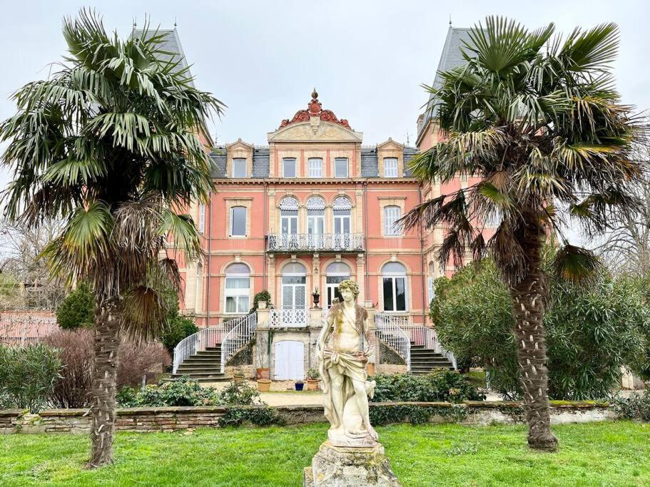 a statue in front of a building with palm trees at L'Antre vue - jacuzzi au château in Belberaud