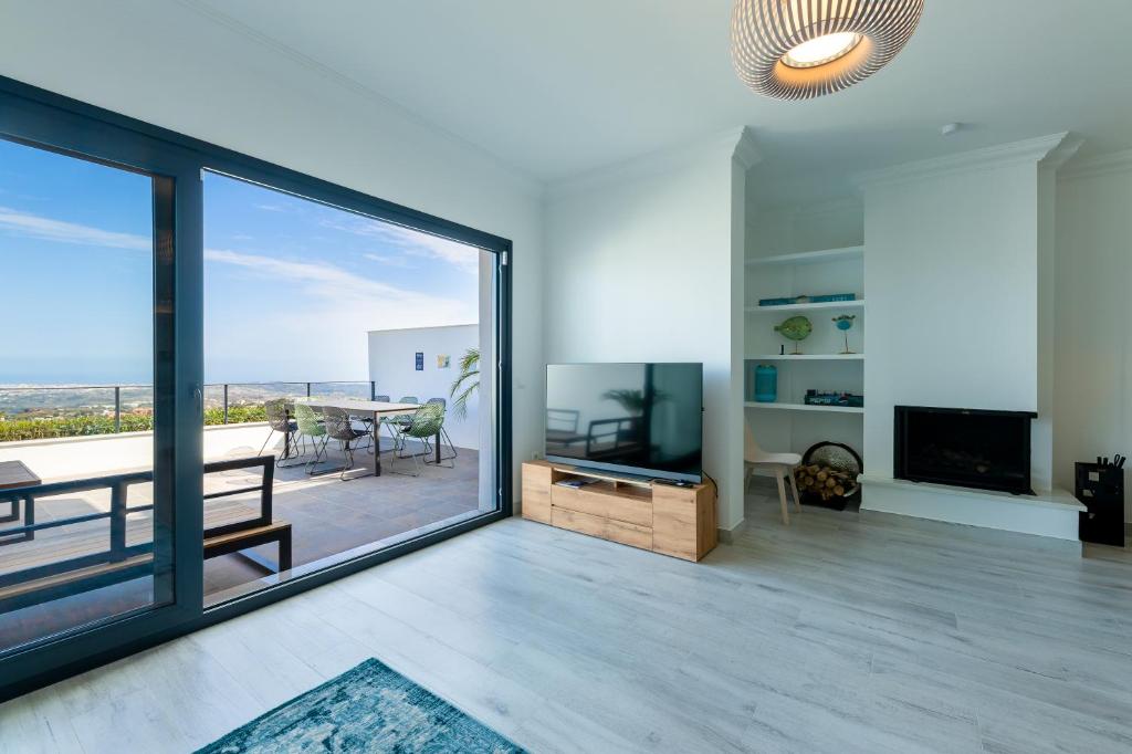 un salon avec une grande fenêtre en verre et une table dans l'établissement Modern Marbella Villa, Pool, Ocean & Mountain View, à La Mairena