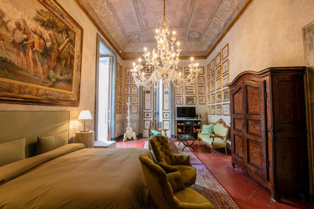 Un dormitorio con una cama grande y una lámpara de araña. en Palazzo Doria Napoli, en Nápoles