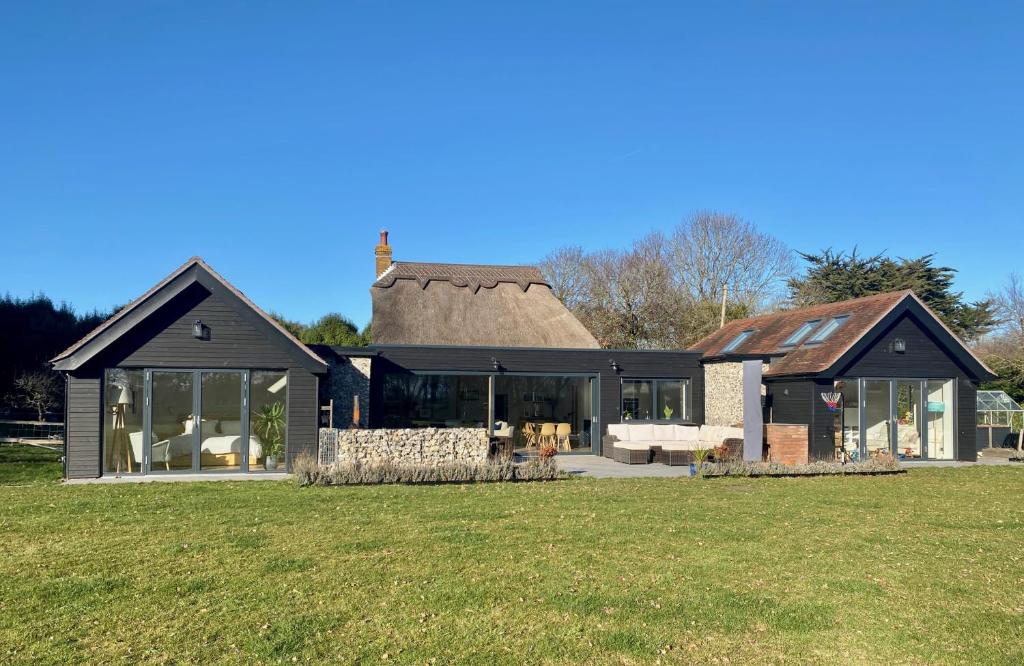 a house with a thatched roof on a field at Luxury Cottage Conversion ~ Close to Beaches in Birdham