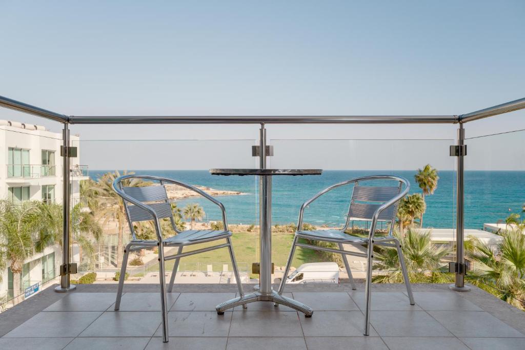 einen Balkon mit einem Tisch, Stühlen und Meerblick in der Unterkunft Stunning one-bedroom apartment with sea views in Protaras
