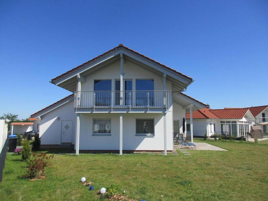 a white house with a balcony and a yard at Villa Kleine Welle in Trent