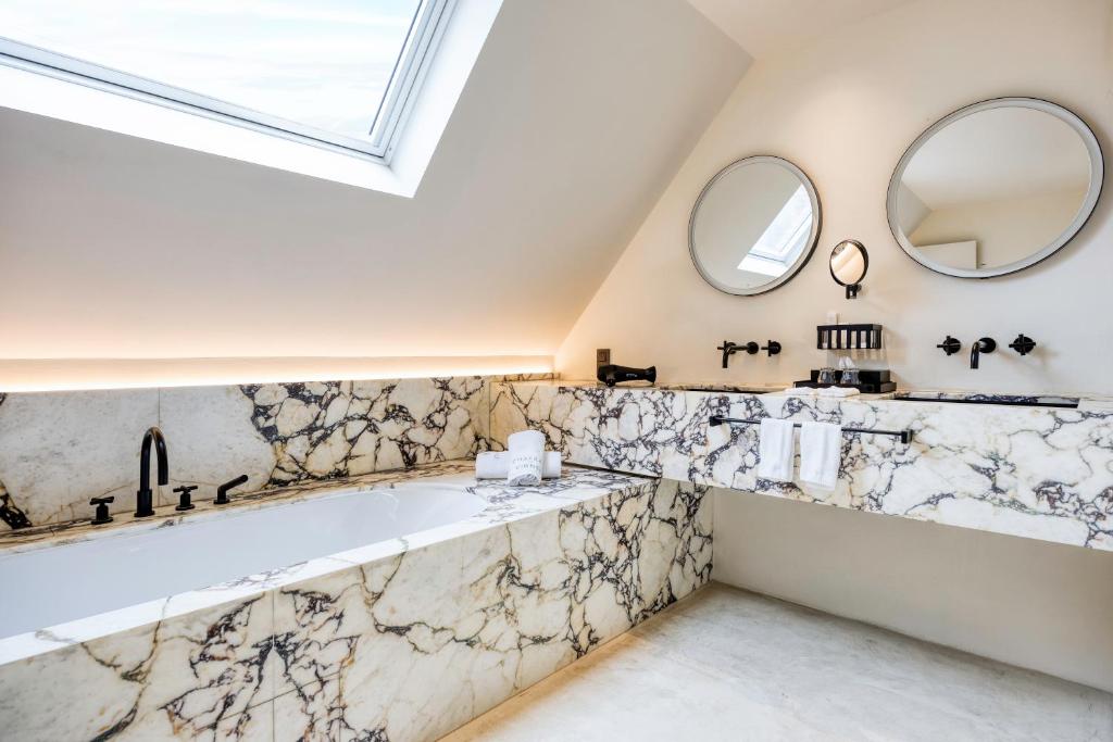een badkamer met een groot bad en 2 spiegels bij Château de Vignée in Rochefort