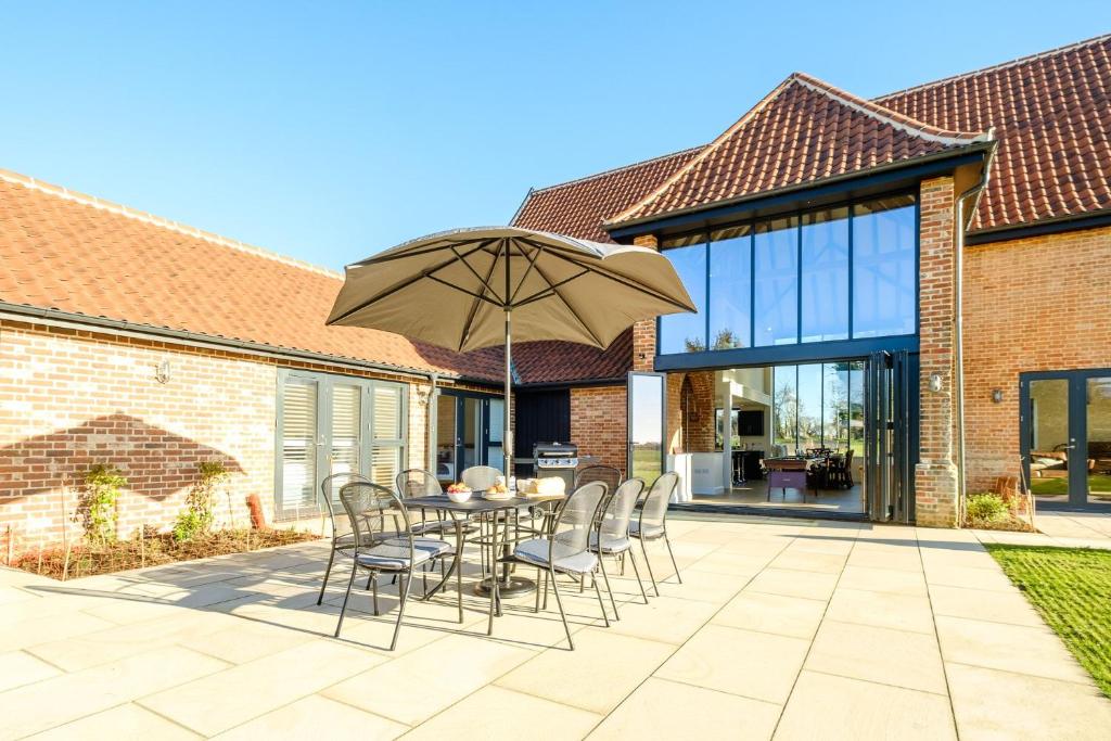 a patio with a table with chairs and an umbrella at Upper Barn in Ufford