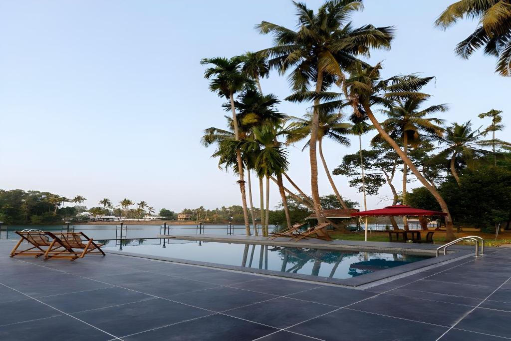 a swimming pool with palm trees and a resort at Lhasa Ayurveda and Wellness Resort - A BluSalzz Collection, Kochi, Kerala in Cochin