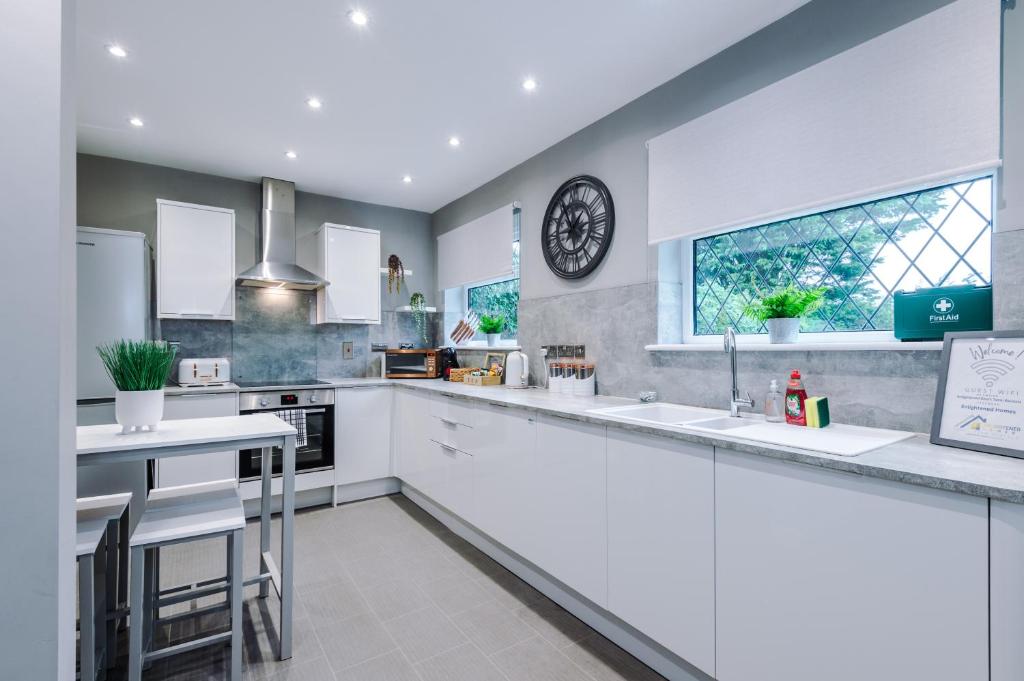a kitchen with white counters and a clock on the wall at Poplar House- Contractor Friendly 3 Bedroom Bright Modern House with a Sofa Bed in Preston