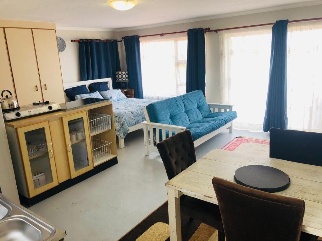 - un salon avec un canapé bleu et un lit dans l'établissement Charming retreat in Danabaai, à Mossel Bay