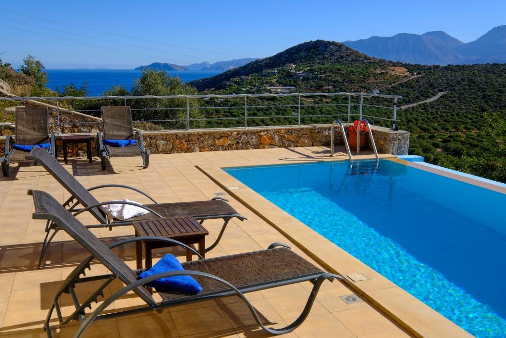 a swimming pool with chairs and a view of the mountains at Villa Poppy in Vathi