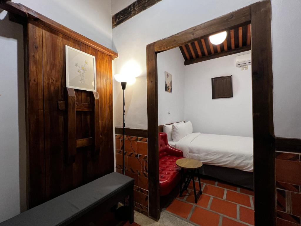 een kleine kamer met een bed en een deur naar een slaapkamer bij 金門古寧歇心苑官宅古厝民宿 Guning Xiexinyuan Historical Inn in Jinning