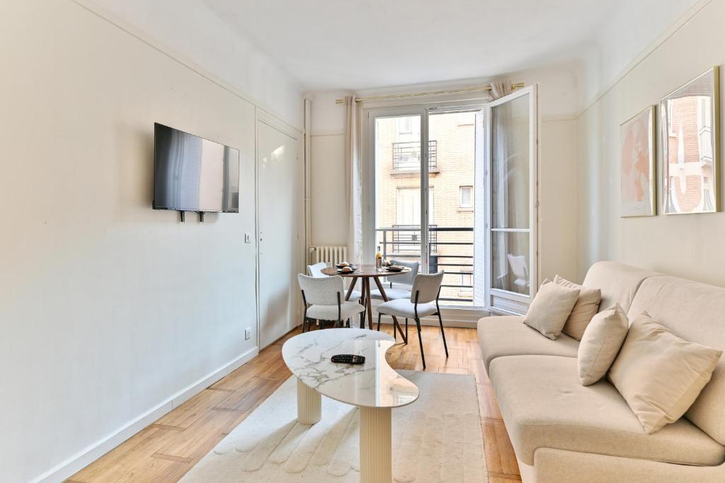 een woonkamer met een bank en een tafel bij Apparement à 5 minutes de Paris - Neuilly in Neuilly-sur-Seine