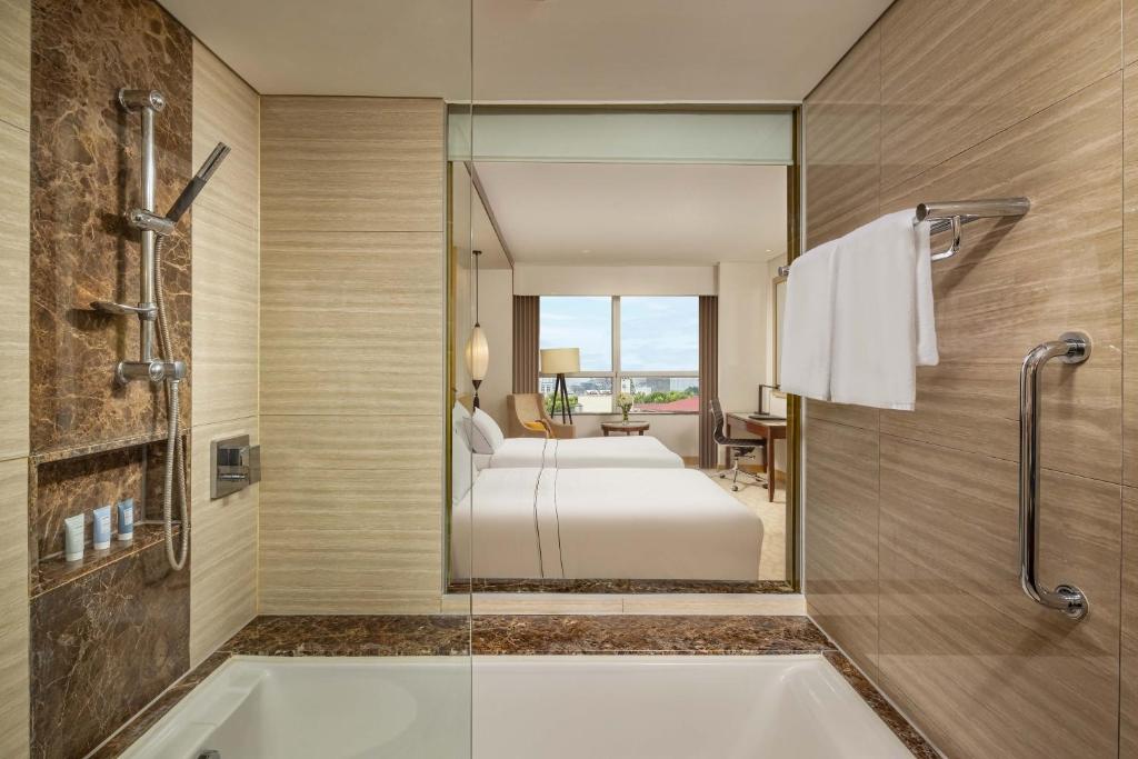 a bathroom with a tub and a bed in a room at Melia Hanoi in Hanoi