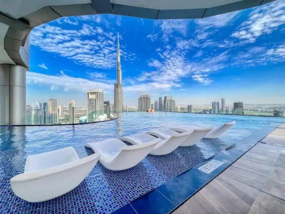 uma piscina com cadeiras brancas no meio do horizonte da cidade em Luxurious one bedroom Apartment em Dubai