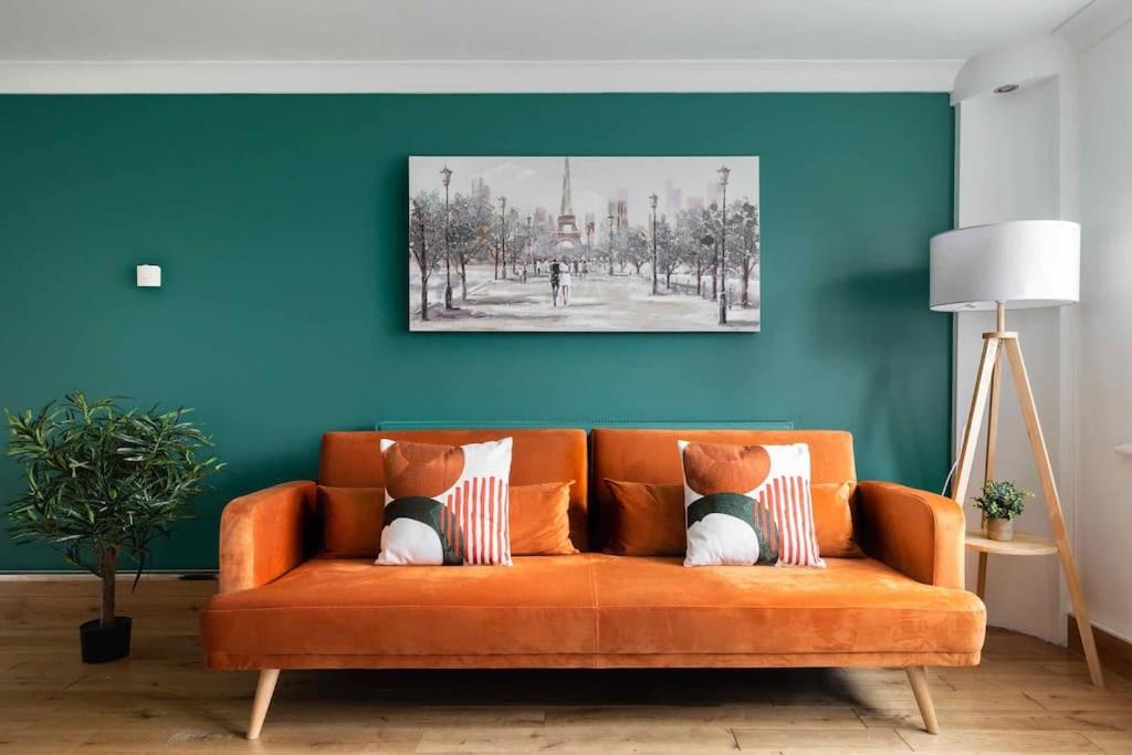ein orangefarbenes Sofa mit zwei Kissen im Wohnzimmer in der Unterkunft Evergreen Cottage Orsett in Orsett