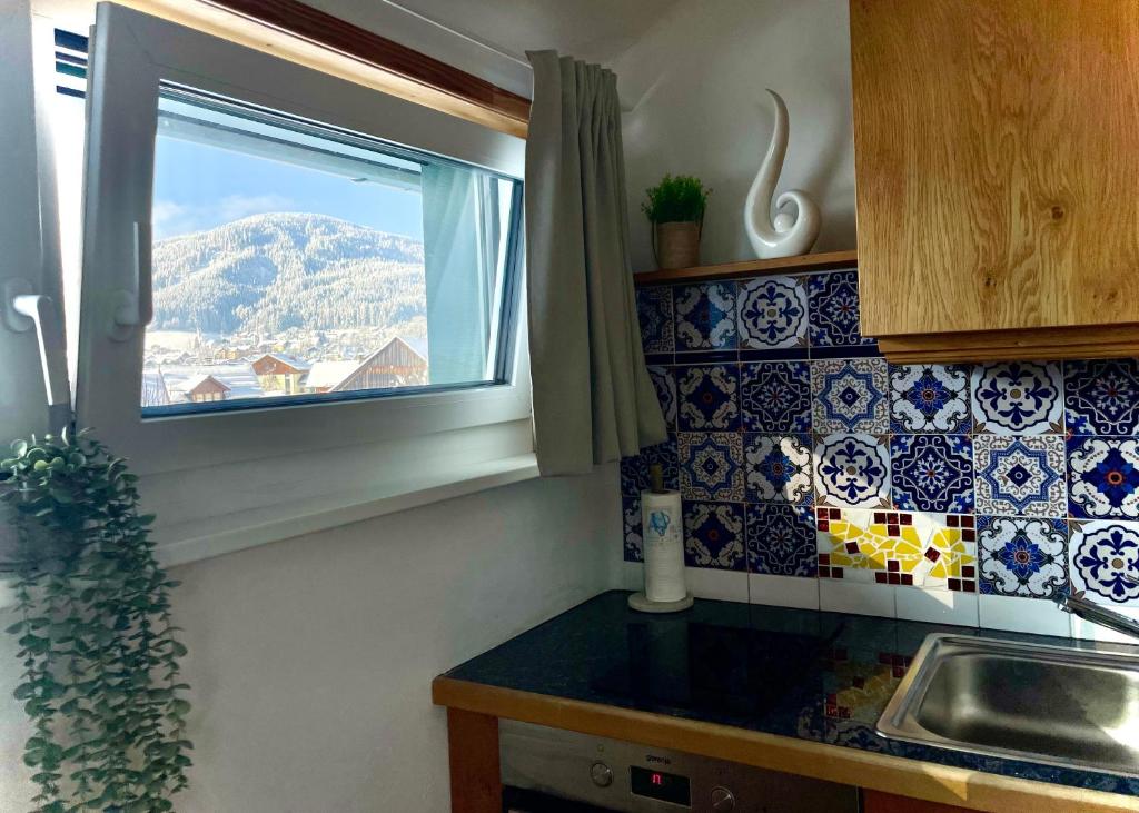 uma cozinha com uma janela com vista para uma montanha em Almsternderl 2.0 - gemütliches Appartment in Gosau em Gosau