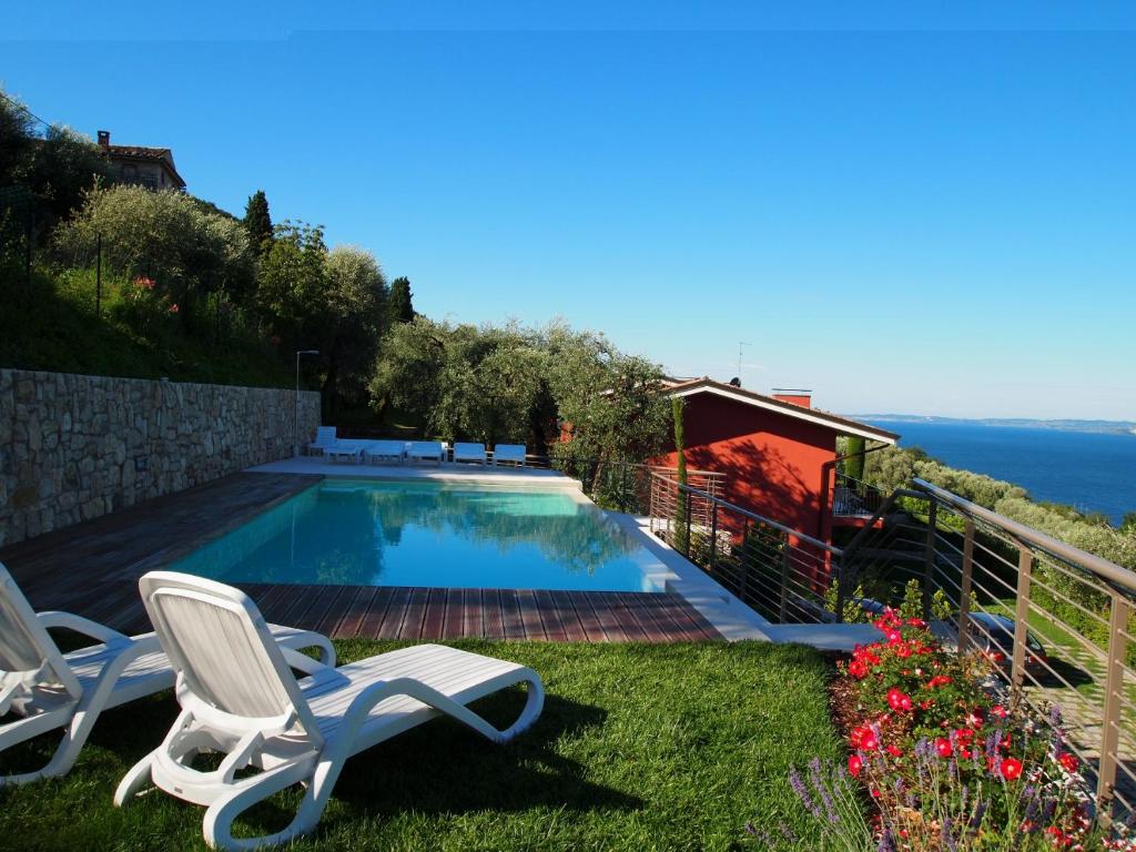 a swimming pool with two chairs and the ocean at Appartamenti Gianni in Torri del Benaco