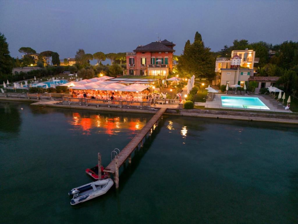 a dock with a restaurant and a boat in the water at Villa Pioppi Hotel in Sirmione