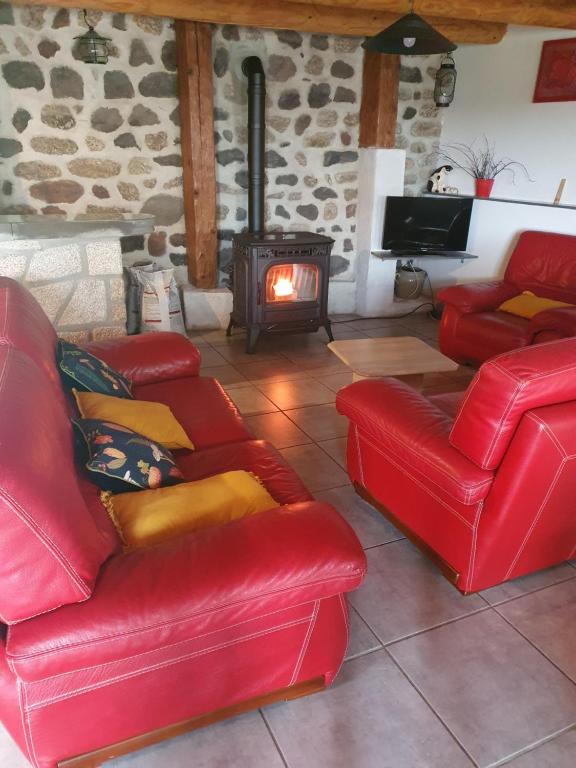 a living room with red leather furniture and a fireplace at " gite Au Pied Du Chapelas" in Le Plagnal