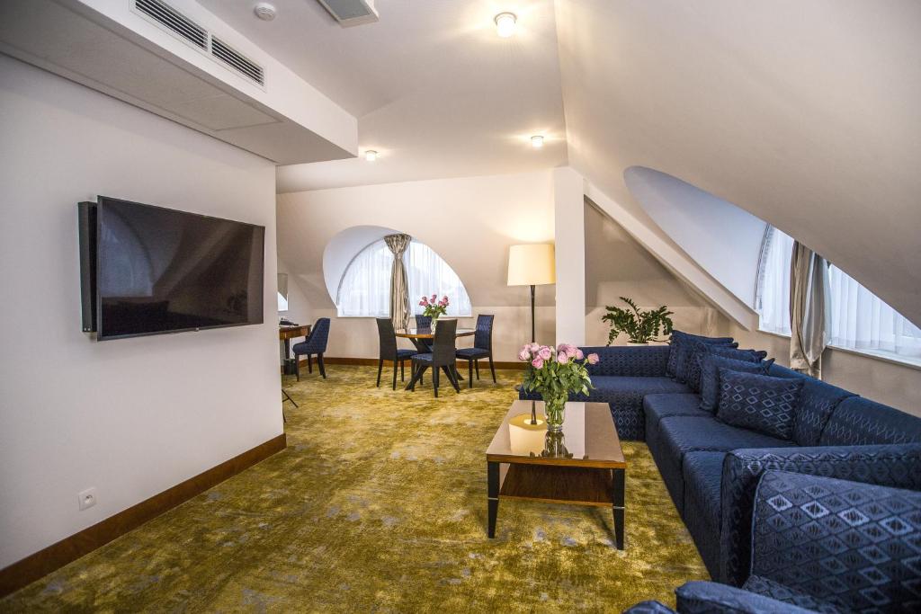 a living room with a blue couch and a tv at Grand Lubicz Uzdrowisko Ustka in Ustka