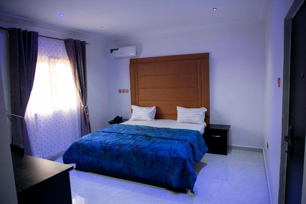 um quarto com uma cama grande e um cobertor azul em Cogent Apartments Single Rooms em Uyo