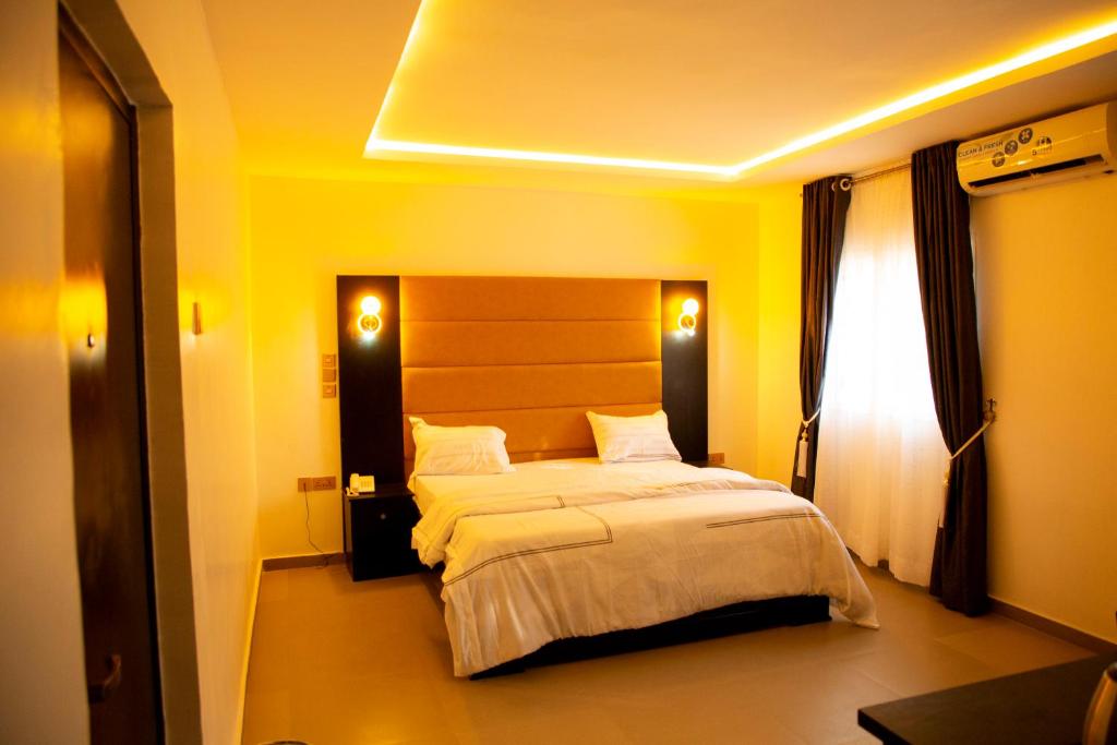 ein Schlafzimmer mit einem großen Bett in einem gelben Zimmer in der Unterkunft Cogent Apartments Single Rooms in Uyo