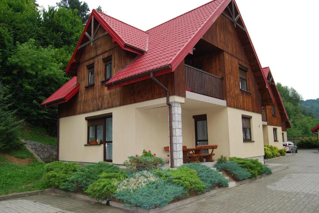 una casa con techo rojo y algunas plantas en Domek nad Muszynką en Muszyna