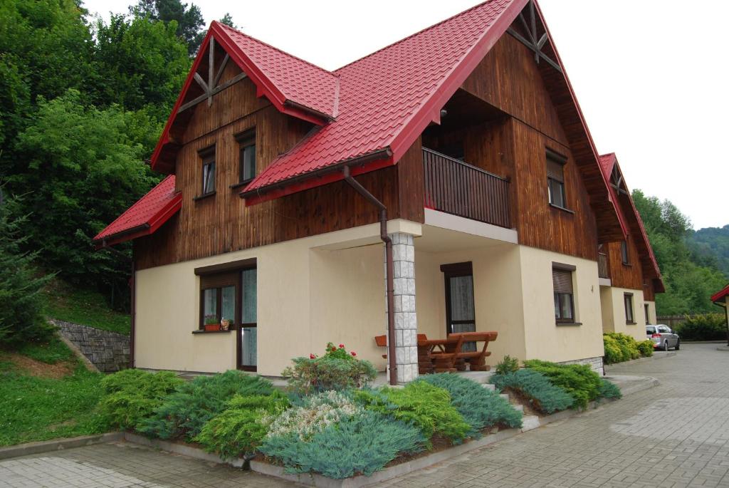 a house with a red roof and some plants at Domek nad Muszynką in Muszyna