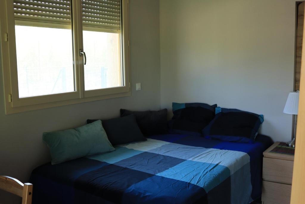 a bedroom with a bed with blue sheets and a window at Les Glycines de Soubize in Lablachère